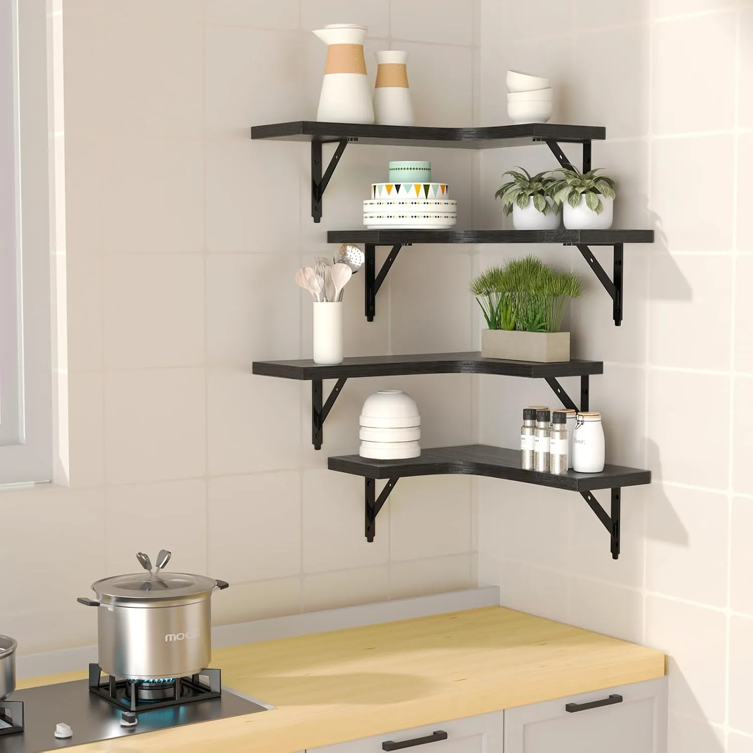 Black corner shelves above a kitchen counter holding plants, jars and dishes